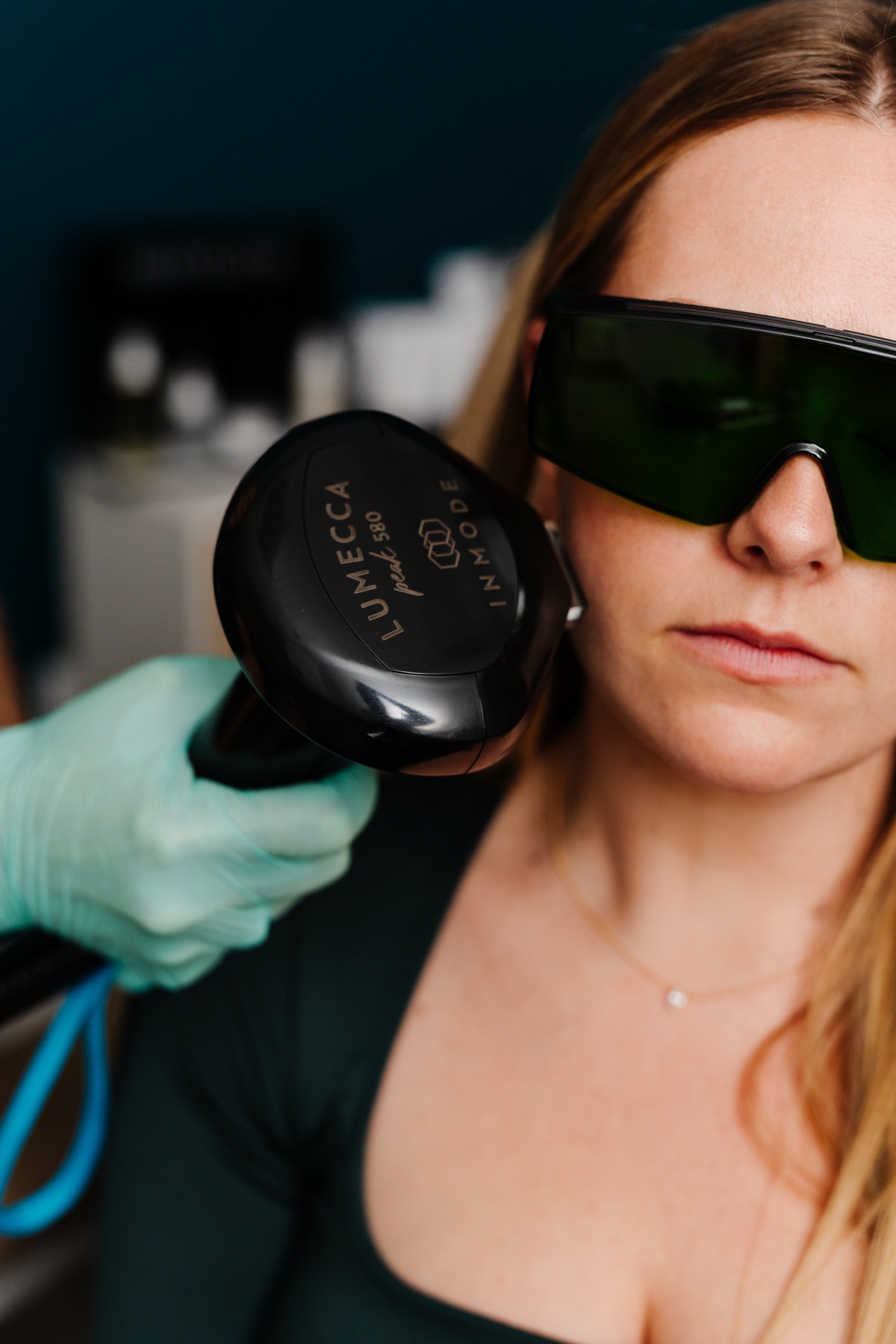 Lumecca IPL handpiece held to a patient's cheek, patient wearing protective eyewear