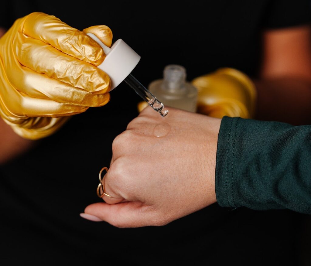 Gloved hand applying a serum to a patient's hand with a dropper